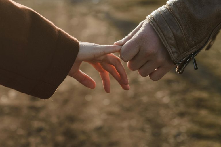 Close-up of two hands connecting, symbolizing love and connection in a warm setting.